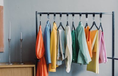 clothes on black metal rack with pairs of footwear on floor