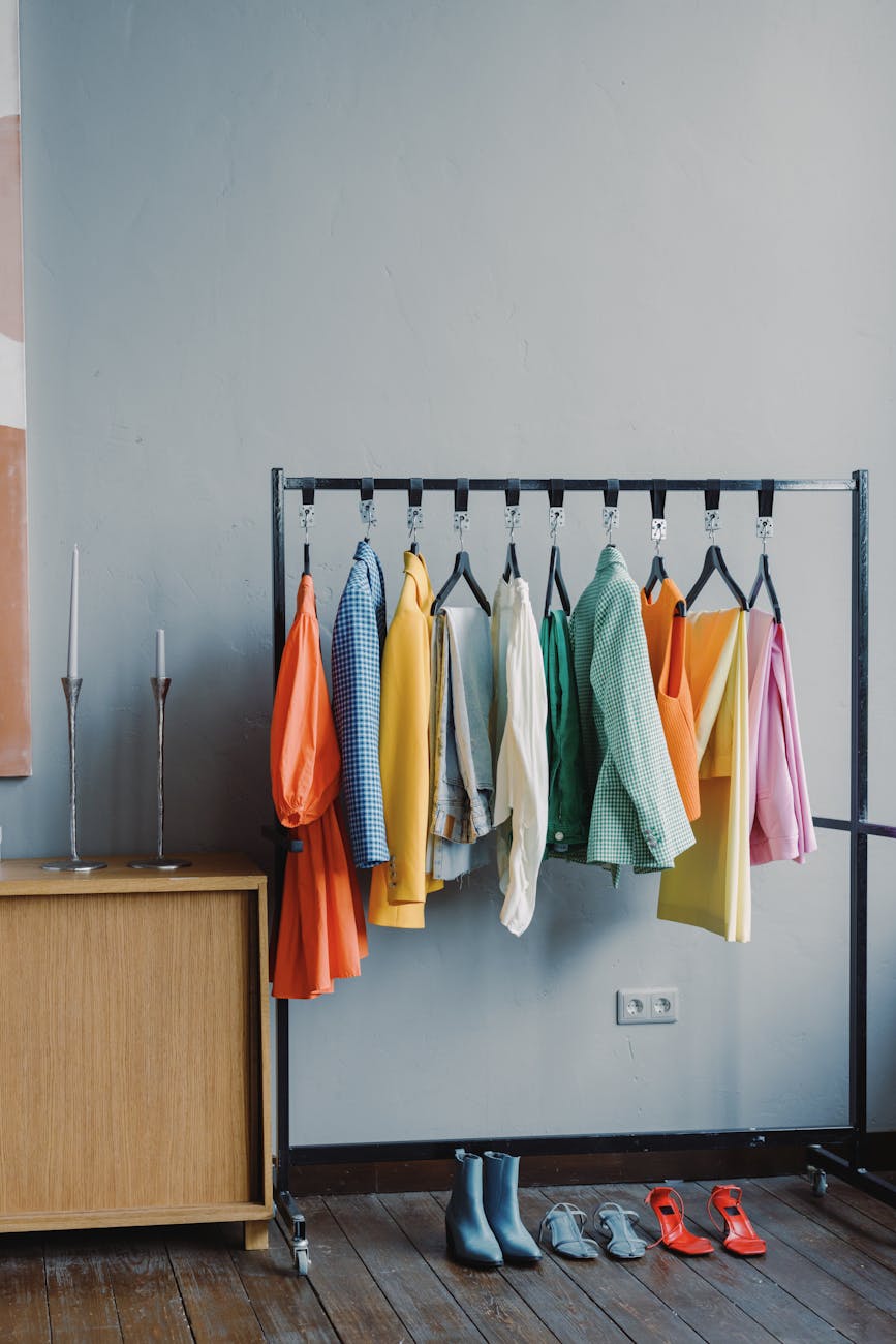 clothes on black metal rack with pairs of footwear on floor